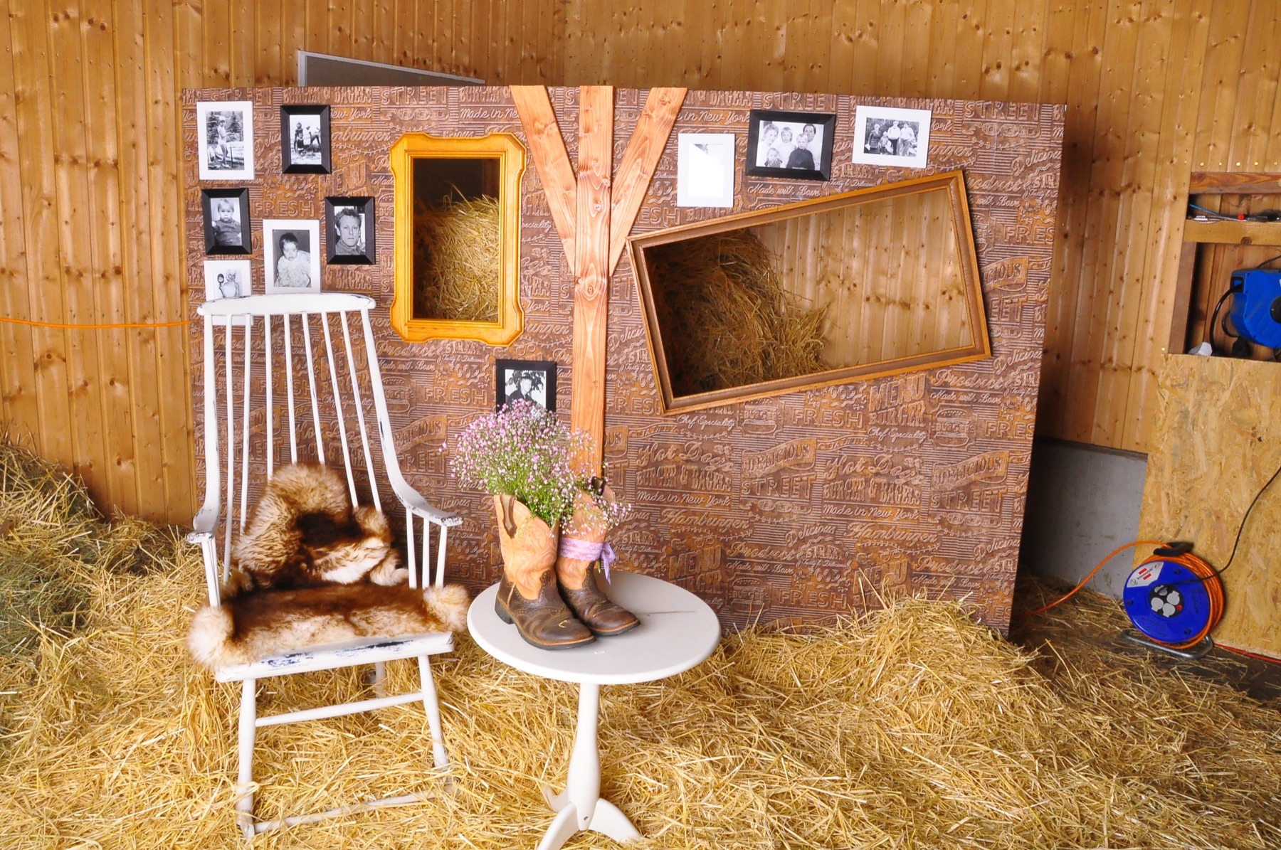 Fotoecke im Stall mit Bilderrahmen, Schaukelstuhl, Westernstiefeln und Stroh